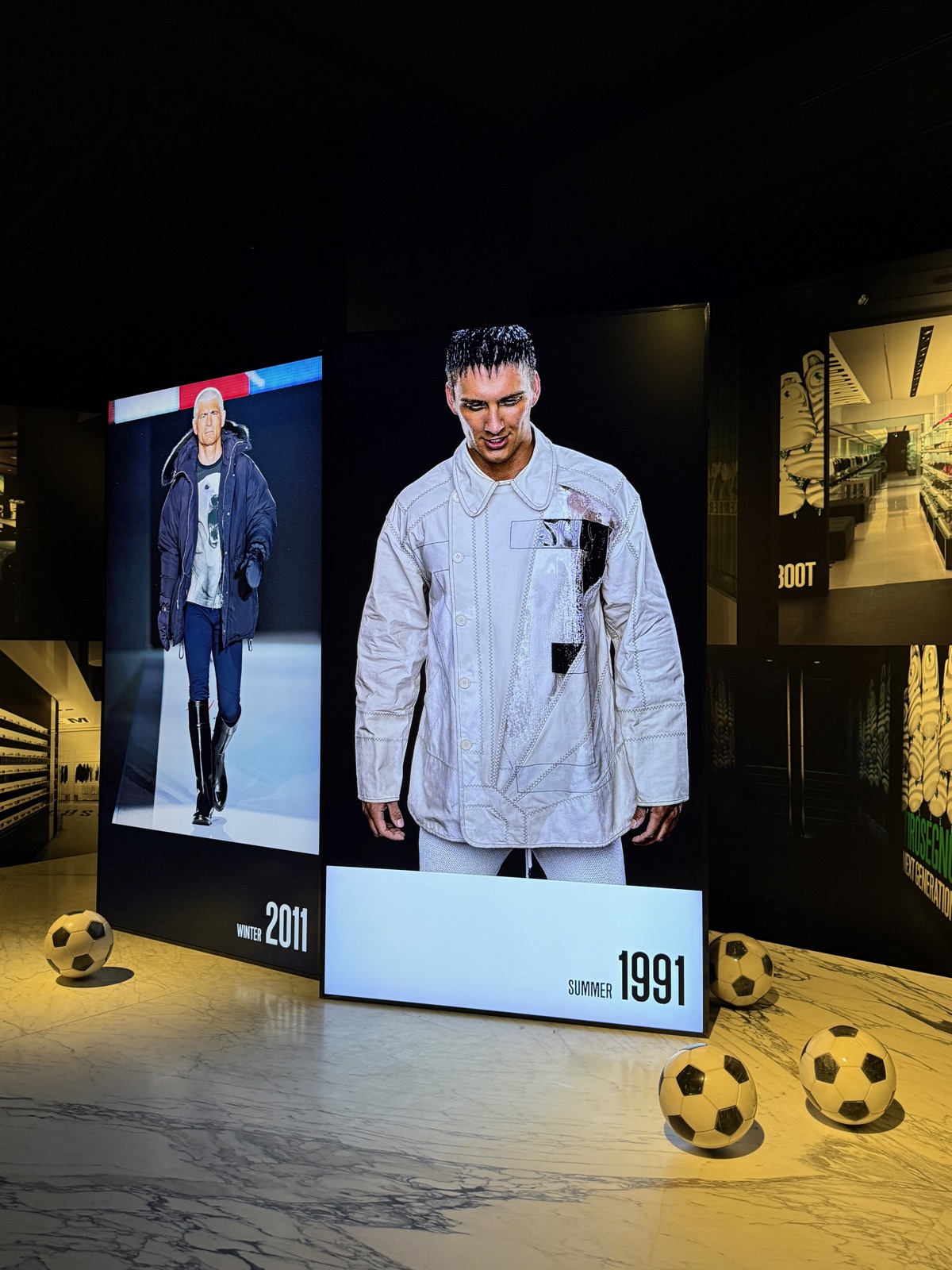 Dirk Bikkembergs's room at MoMu: backlit panels of runway looks and footballs scattered across a marble floor.