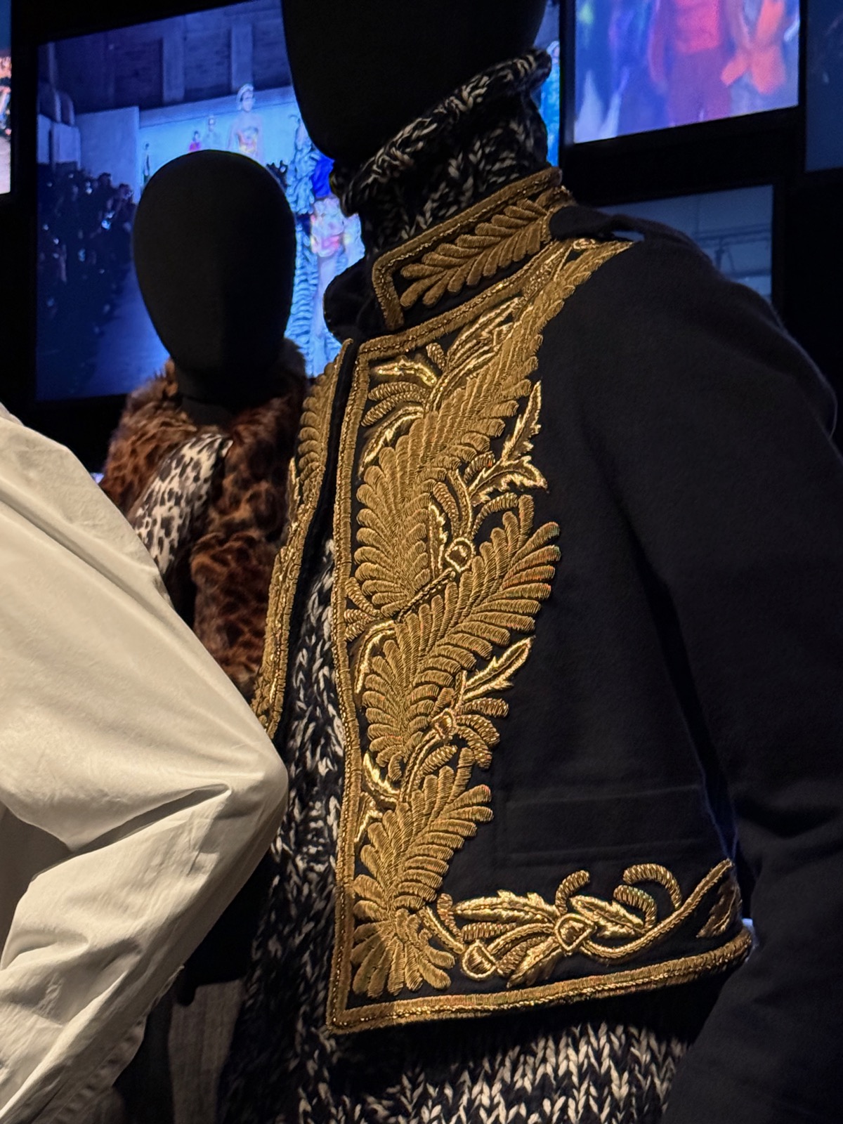A Dries Van Noten coat with dense gold embroidery, displayed beside dark and leopard-print pieces.