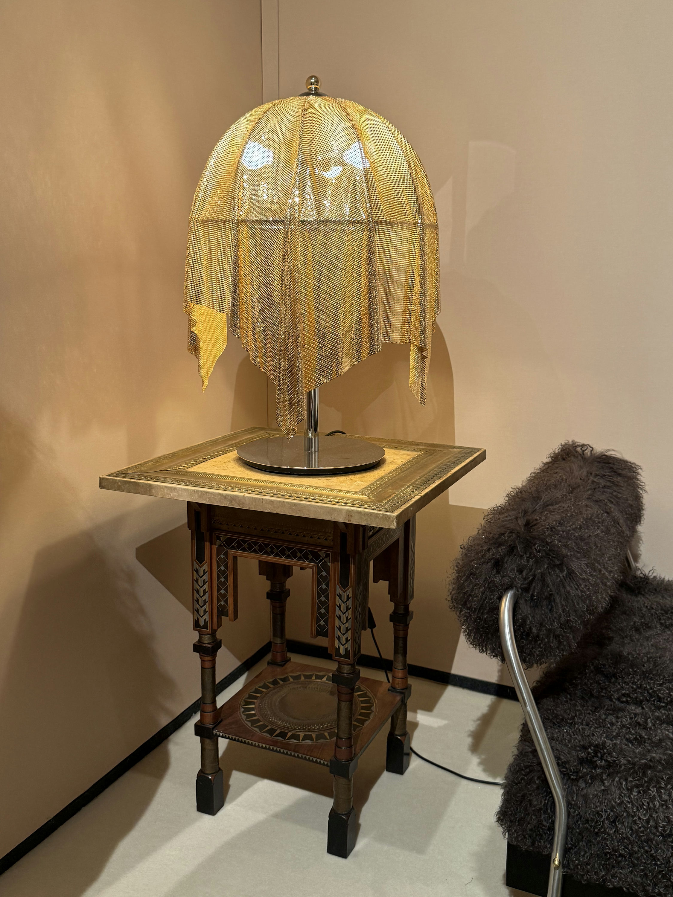 A gilded fringed-mesh table lamp standing on Carlo Bugatti's inlaid turn-of-the-century table at the Yves Salomon Éditions stand.