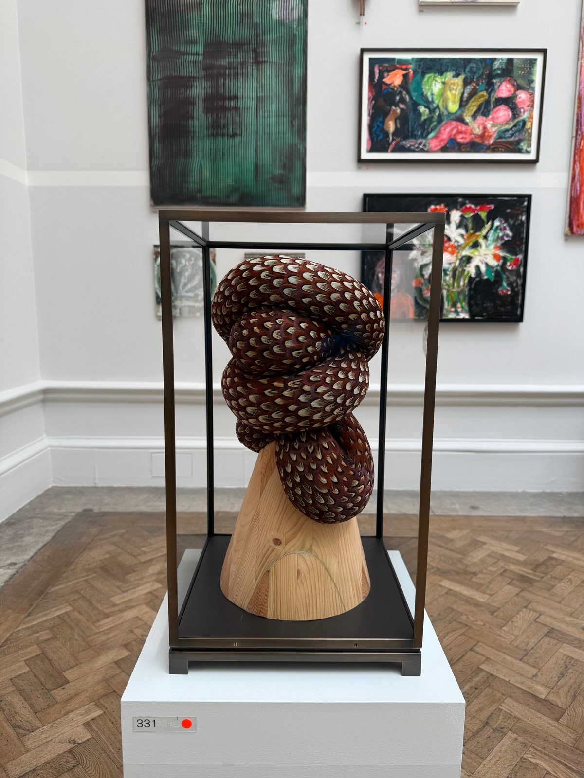 A coiling sculpture made of pheasant feathers on a pine base by Kate MccGwire.