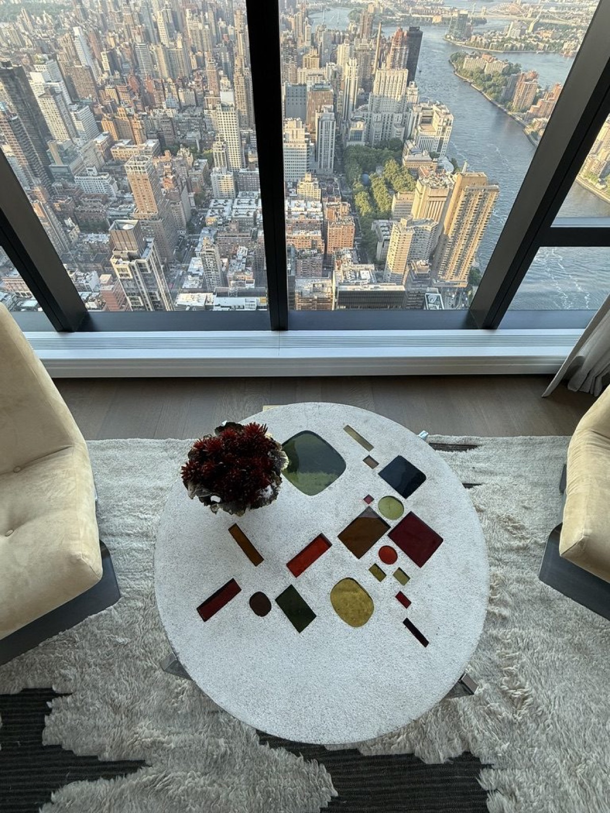 A round table inlaid with coloured glass, seen from above between two suede chairs.