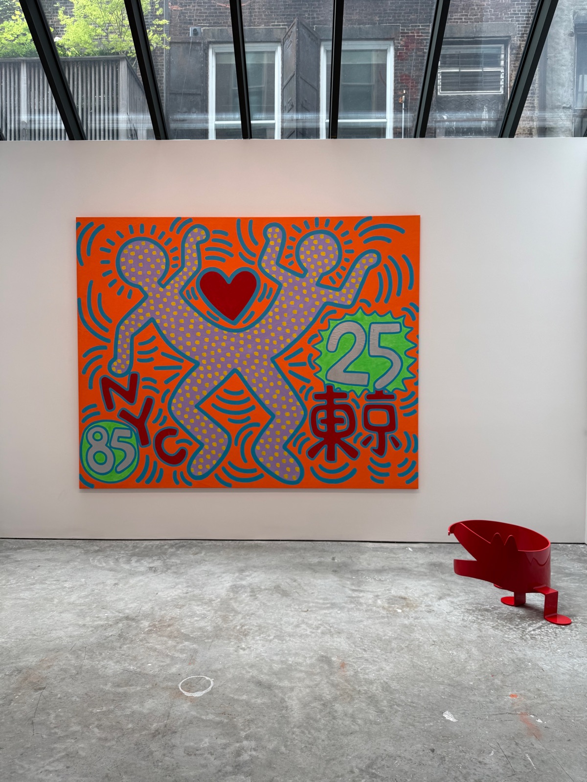 A bold orange Keith Haring canvas with two outlined figures, a red heart, and 'NYC 85 / Tokyo 25' lettering.
