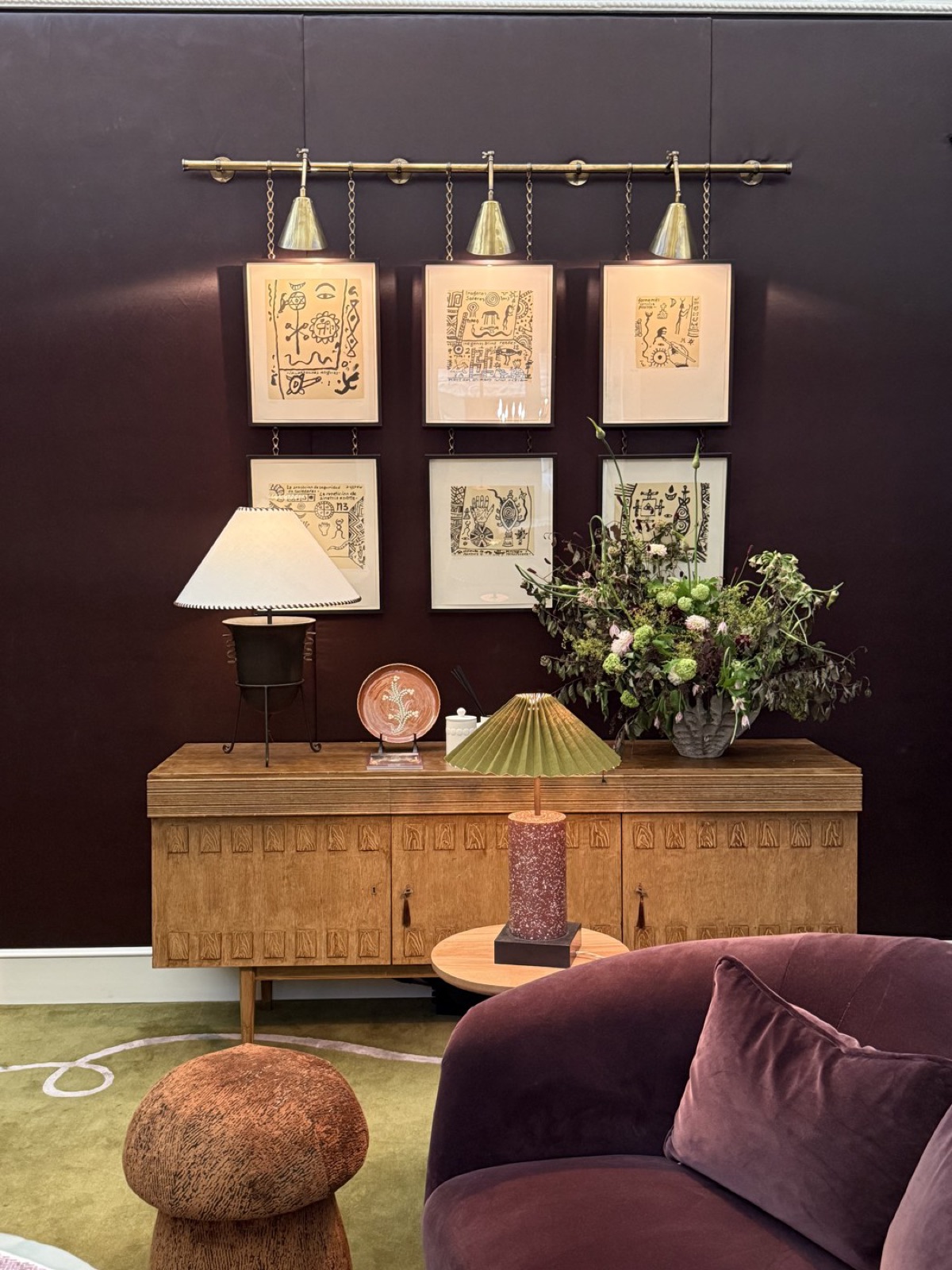 Six small Alan Davie works hung in two rows on a brass picture rail in Studio Duggan's brown speakeasy room.